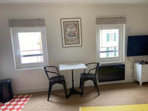 um quarto com duas cadeiras e uma mesa e duas janelas em Bel appartement, Oiseau 1 em Niort