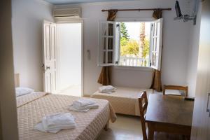 Habitación con 2 camas, mesa y ventana en Sigma Hotel, en Paralia Vrachou