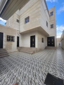 a large white building with a stone floor and stairs at فلل فندقية بمدينة تنومة in Ithnayn