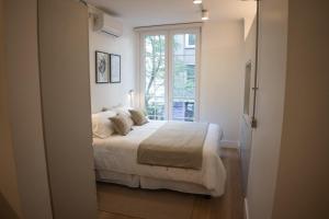 a white bedroom with a bed and a window at Studio en la Calle Monjitas Corazon de Santiago in Santiago