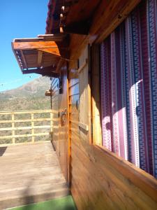 una veranda in legno su una casa con una montagna sullo sfondo di La ferme familiale Atmani a El Kseur