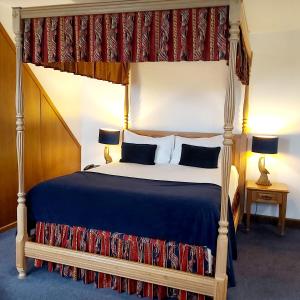 1 dormitorio con cama con dosel y edredón azul en The Old Ram Coaching Inn en Tivetshall Saint Margaret