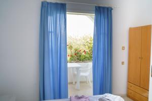 1 dormitorio con cortinas azules y mesa con ventana en Sigma Hotel, en Paralia Vrachou