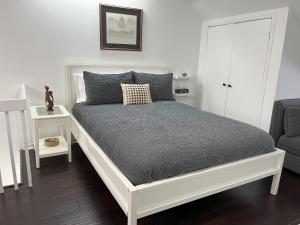 ein weißes Bett in einem Zimmer mit Stuhl in der Unterkunft Bright, Private, Peaceful Suite with Retail Conveniences Steps Away in Toronto