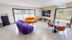uma sala de estar com um sofá roxo e uma mesa em Villa architecte luxe Drome provençale em Montélimar