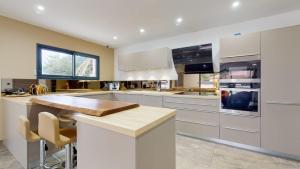 eine Küche mit weißen Schränken und einer hölzernen Arbeitsplatte in der Unterkunft Villa architecte luxe Drome provençale in Montélimar