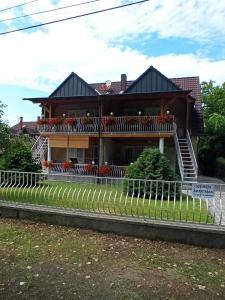a house with a balcony and a fence at Szemes Apartman Balaton in Balatonszemes