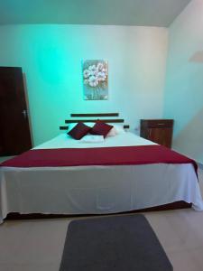 a bedroom with a large bed with red and white sheets at Mallika City Villa in Negombo