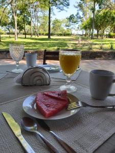 a table with a plate of meat and a glass of orange juice at Don Patron hotel&eventos in Villarrica