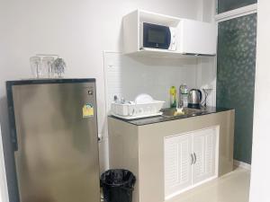 una piccola cucina con frigorifero e forno a microonde di บ้านครูกอล์ฟ a Kanchanaburi