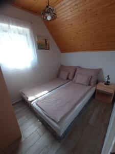 Cama en habitación pequeña con ventana en Szemes Apartman Balaton en Balatonszemes