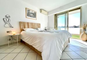 - une chambre avec un grand lit et une grande fenêtre dans l'établissement Magnifique 2P vue mer Terrasse Parking, à Juan-les-Pins