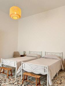 two beds in a white room with a lamp at Casetta Bianca con Giardino in Posada
