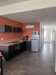 eine Küche mit orangefarbenen Wänden und einem weißen Kühlschrank in der Unterkunft maison cosy centre-ville in Lens
