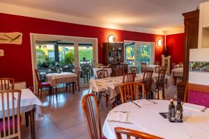 een restaurant met tafels en stoelen en rode muren bij Albergo Cristina in Lazise