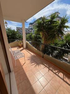 Elle comprend un balcon avec une chaise et des palmiers. dans l'établissement Villa Maria Palese, à Bari