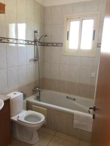 een badkamer met een toilet, een bad en een raam bij Budget Escape to the seaside in Larnaka