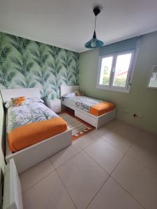 een slaapkamer met 2 bedden en tropisch behang bij Casina verde manzana in Villaviciosa