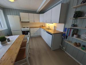 a kitchen with white cabinets and a wooden table at Romslig leilighet in Tromsø