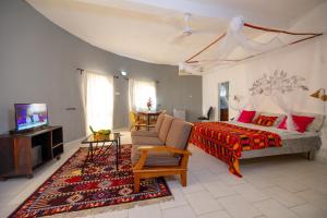 um quarto com uma cama, um sofá e uma televisão em Afro Garden Hotel em Sere Kunda