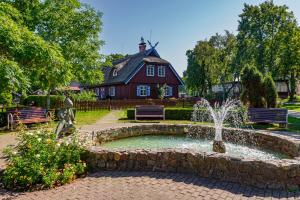 einen Brunnen in der Mitte eines Gartens mit einem roten Haus in der Unterkunft Vila Banga in Nida