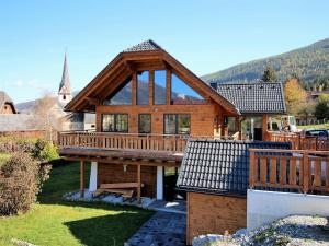 duży drewniany dom z tarasem i kościołem w obiekcie Alpinn Wellness w mieście Sankt Margarethen im Lungau
