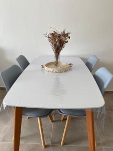 Biały stół z niebieskimi krzesłami i wazonem kwiatów w obiekcie Departamento Entre Rios w mieście Santa Rosa