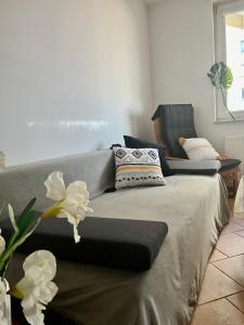 a bed in a room with a couch and flowers at Apartament WITOMINO in Gdynia
