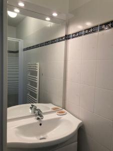 ein weißes Badezimmer mit Waschbecken und Spiegel in der Unterkunft Appartement cosy proche rue piétonne et plages in Capbreton + 12 Fotos