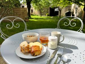 uma mesa com um prato de croissants e uma chávena de café em Closerie la Fontaine em Savigné-sur-Lathan