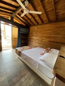Cama en habitación de madera con ventilador de techo en Finca Hotel La Manuela, en Arboletes