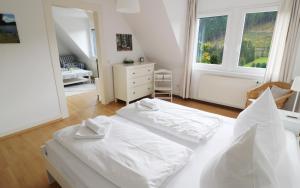 a white bedroom with two beds and a dresser at Ferienwohnung im Haus Rhea am Südhang- Feldberg- Falkau in Vorderfalkau