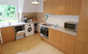 a kitchen with wooden cabinets and a sink and a microwave at Ferienwohnung im Haus Rhea am Südhang- Feldberg- Falkau in Vorderfalkau