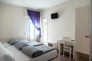 a bedroom with a bed and a desk and a window at Albergo Cristina in Lazise