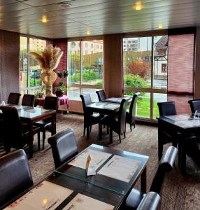 een restaurant met tafels en stoelen en een groot raam bij The Originals City, Hôtel Le Forum, Strasbourg Nord in Schiltigheim
