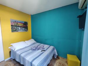 1 dormitorio con 1 cama con pared azul y amarilla en Pousada Sereia Tropical, en Guarujá