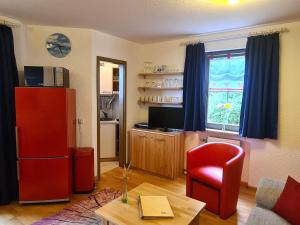 ein Wohnzimmer mit einem roten Kühlschrank und einem roten Stuhl in der Unterkunft Fewo 5 - Residenz Schauinsland, Sauna, E-Ladestation, Todtnauberg bei Feldberg in Todtnauberg
