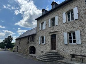 un bâtiment en pierre avec un banc devant lui dans l'établissement LA VIEILLE AUBERGE, à Saint-Geniez-ô-Merle