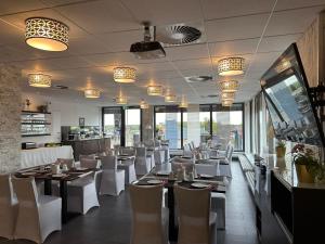 ein Restaurant mit weißen Stühlen, Tischen und Fenstern in der Unterkunft Hotel Efcannos Dornberg Carree in Vechelde