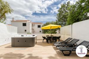 un patio con bañera de hidromasaje, mesa y sillas en Villa Bellagio en Albufeira