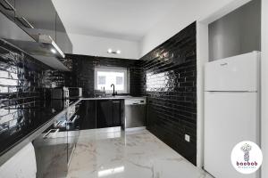 uma cozinha com paredes de tijolos negros e um frigorífico branco em Villa Bellagio em Albufeira