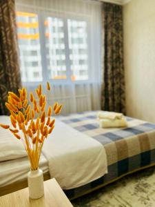 um quarto com uma cama e um vaso de flores sobre uma mesa em Уютные апартаменты в ЖК Акварель em Almaty