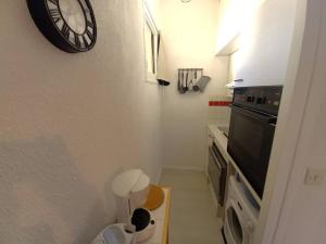a bathroom with a clock on the wall next to a stove at Saint Georges de Didonne - FAITES UNE HALTE - STUDIO - quartier boisé in Saint-Georges-de-Didonne