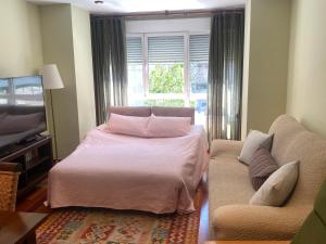 ヒホンにあるPoniente Beachのベッドルーム1室(ベッド1台、ソファ、窓付)