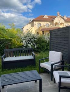 two benches and a chair on a patio with a house at Le Cottage Apaisant in Ardon