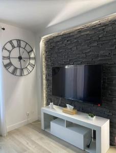 a living room with a tv and a clock on a wall at Le Cottage Apaisant in Ardon