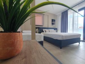 a bedroom with two beds and a potted plant on a table at Olea Luxury Suites in Asprovalta