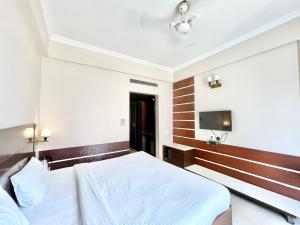 a bedroom with a bed and a flat screen tv at HOTEL JANHVEE INN ! VARANASI - Forɘigner's Choice ! fully Air-Conditioned hotel with Parking availability, near Kashi Vishwanath Temple, and Ganga ghat in Varanasi