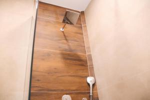y baño con ducha y suelo de madera. en Hotel Rozafa, en Suharekë