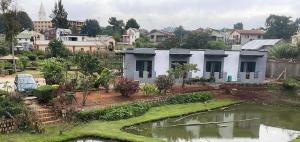 a house with a pond in front of a city at Dream's Hôtel in Antsirabe